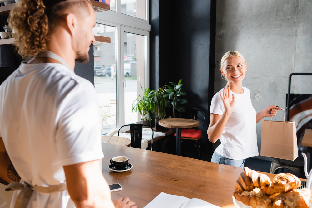 woman-waving-goodbye-to-server-in-cafe