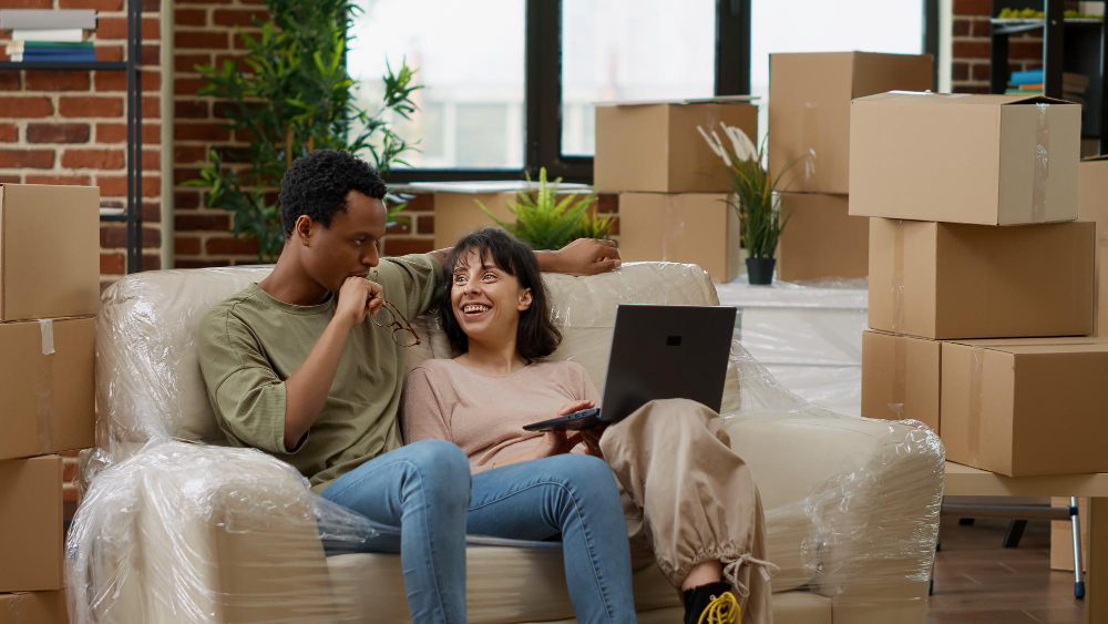 Photo-of-couple-sitting-in-new-house-with-boxes-after-buying-house-with-NHG