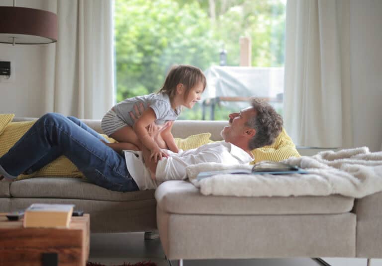 Photo-of-man-who-moved-to-the-Netherlands-with-child-crawling-on-lap-lying-on-couch-after-taking-out-different-types-of-insurance-in-the-Netherlands