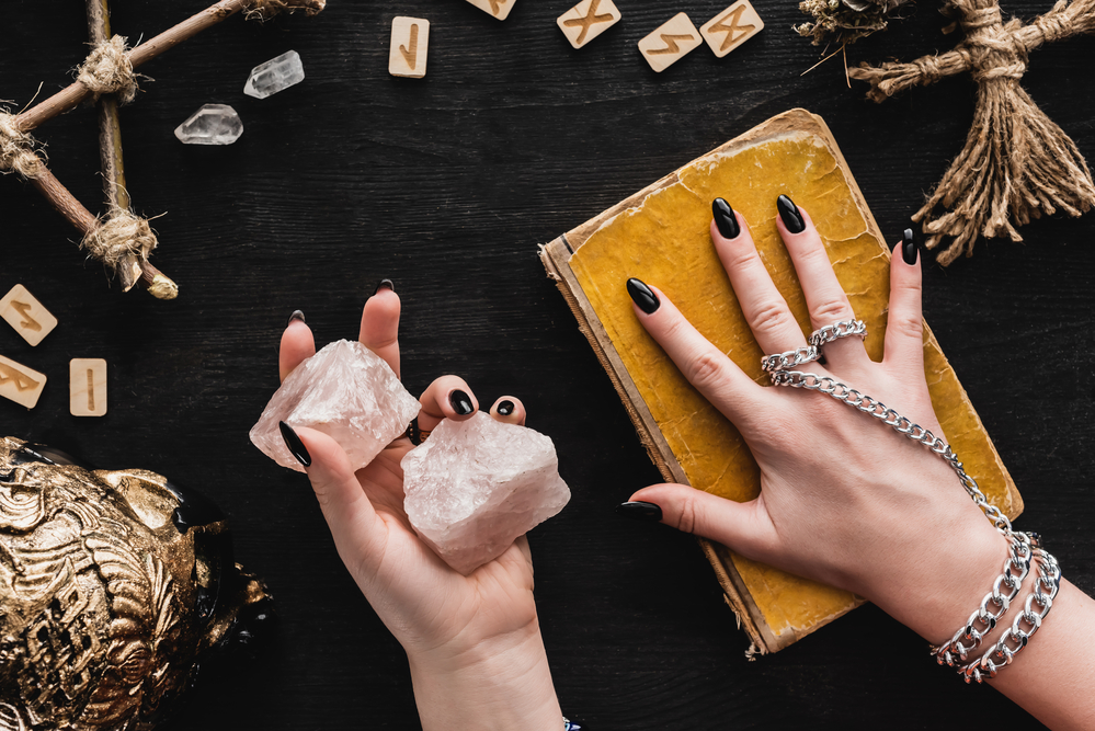 photo-of-female-hands-resting-on-witchcraft-book-and-holding-crystals