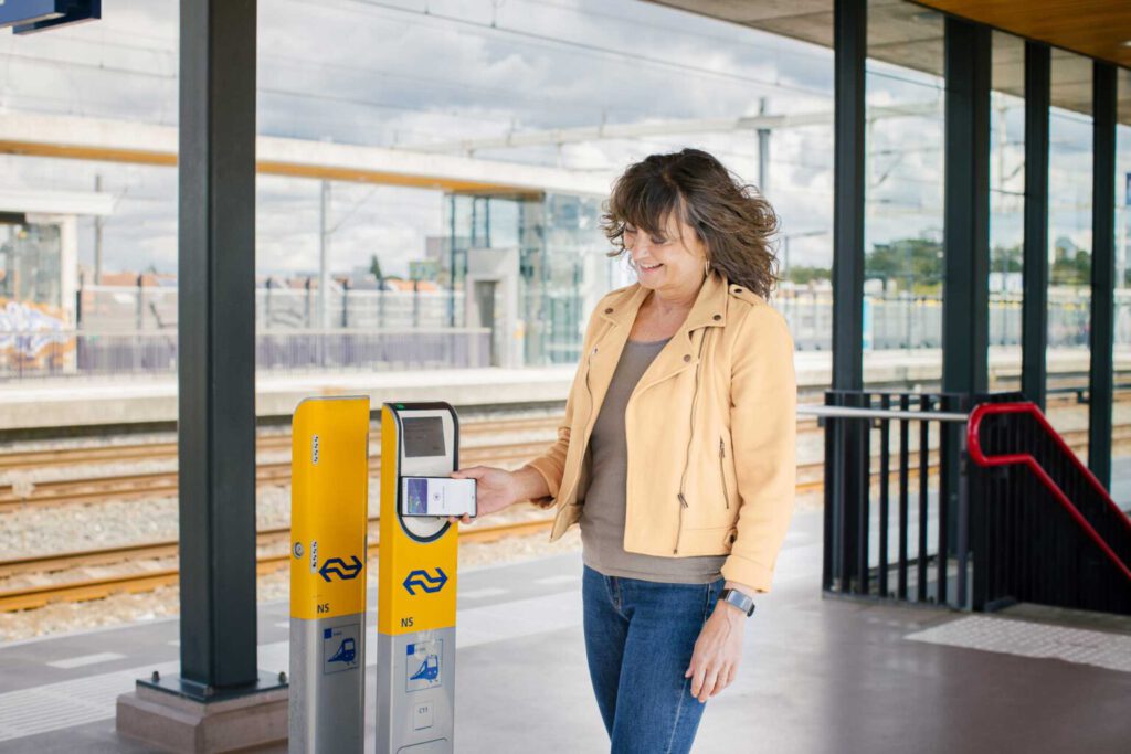 은행 카드로 네덜란드 대중 교통을 체크인하는 방법을 찾는 여성 
