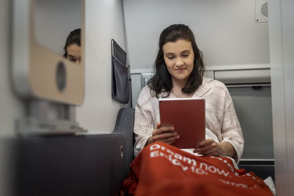 photo-of-woman-relaxing-reading-happily-on-new-nightjet-train-with-red-blanket-over-legs
