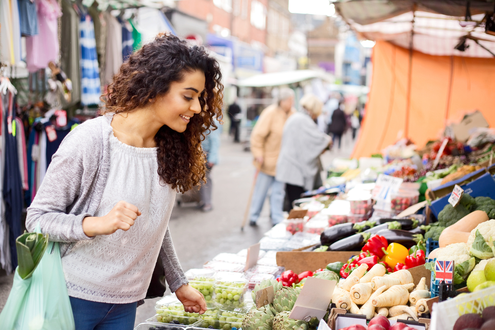 woman-walking-in-street-market-looking-at-fruits-and-vegetables