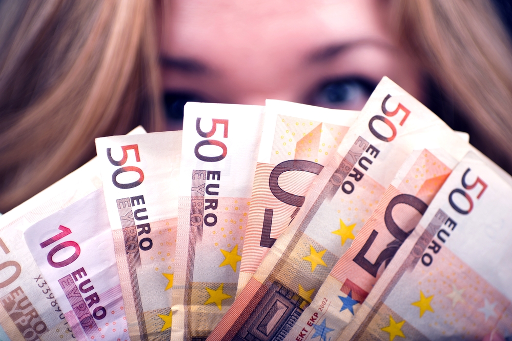Woman-holding-up-a-fan-of-fifty-euro-bills-before-her-face