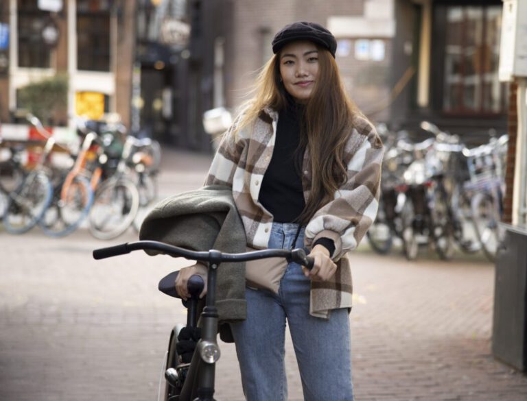 Woman-with-bike-insurance-in-the-netherlands-standing-in-street-holding-bike