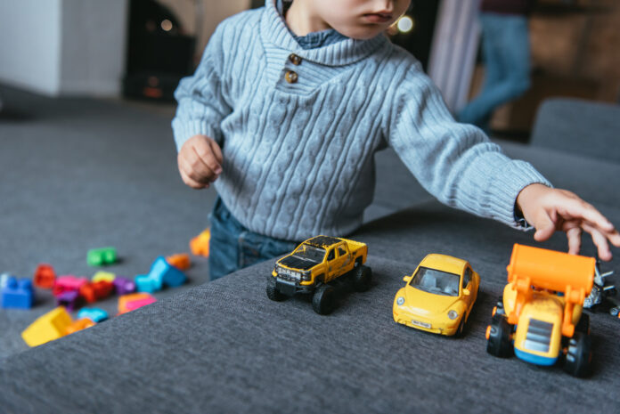 Young-playing-with-toy-cars-on-the-couch