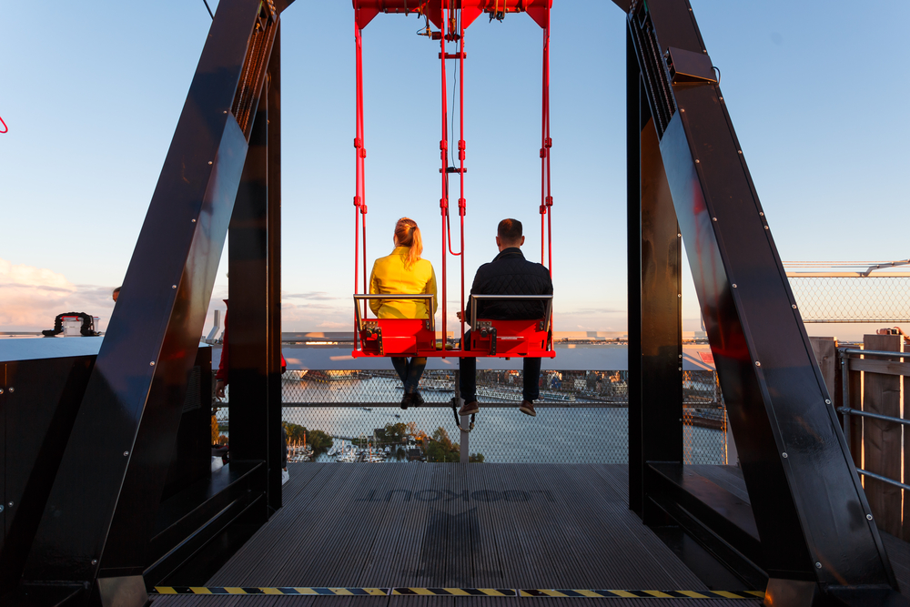 Young-couple-on-the-swing-on-the-roof-of-tower-A'dam-at-sunset-time