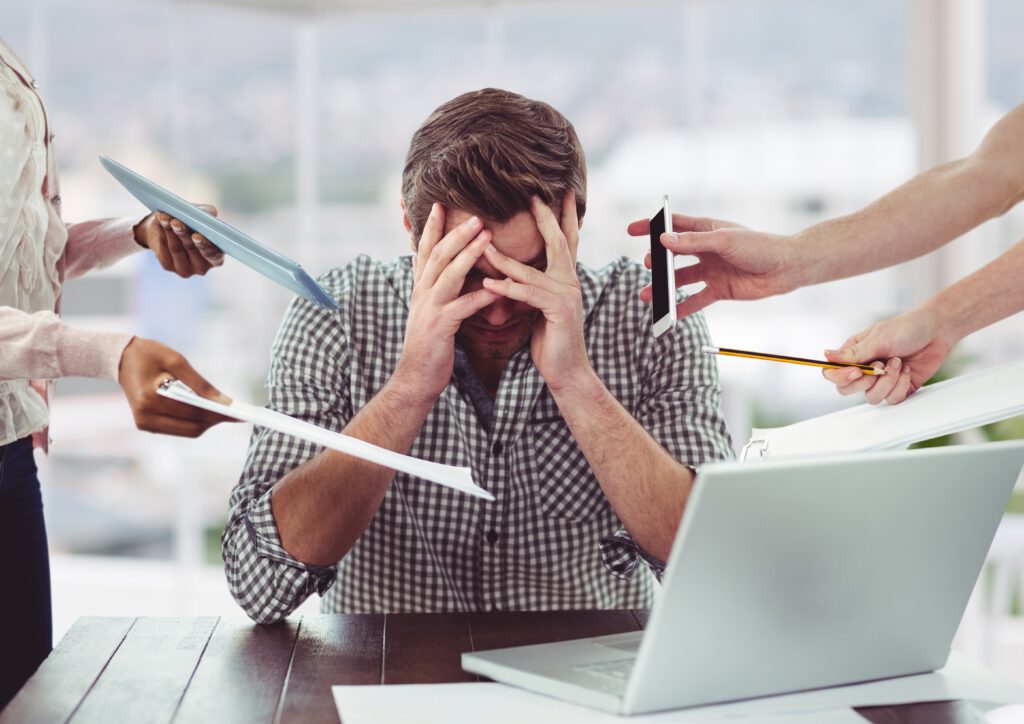 Young-working-man-stressed-out-with-tasks-being-given-to-him-by-phone-and-papers