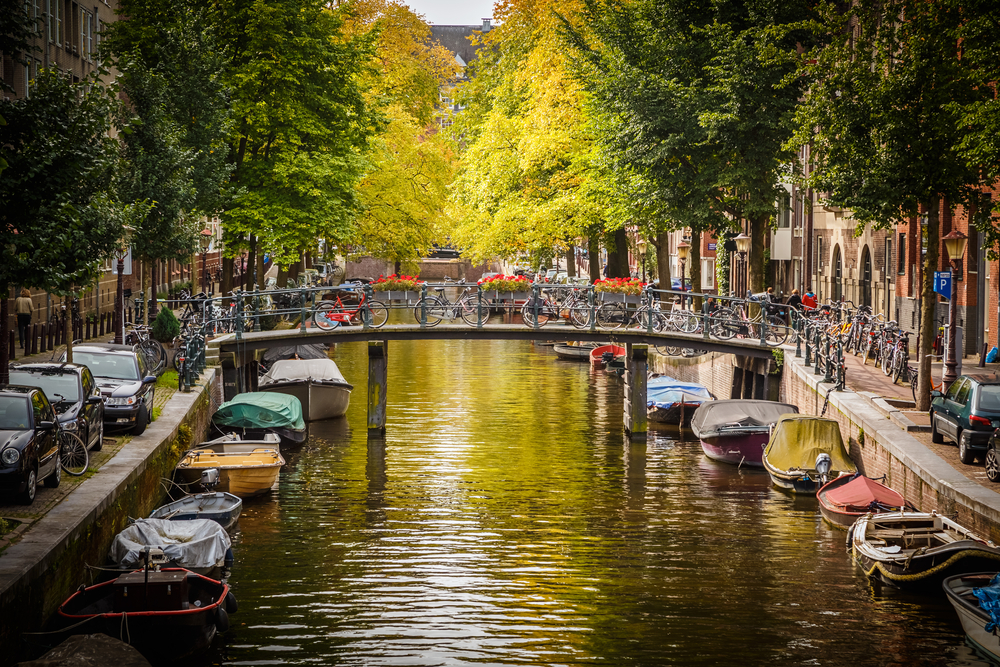 photo-of-amsterdam-canal-with-boats-and-a-bridge-with-parked-bikes