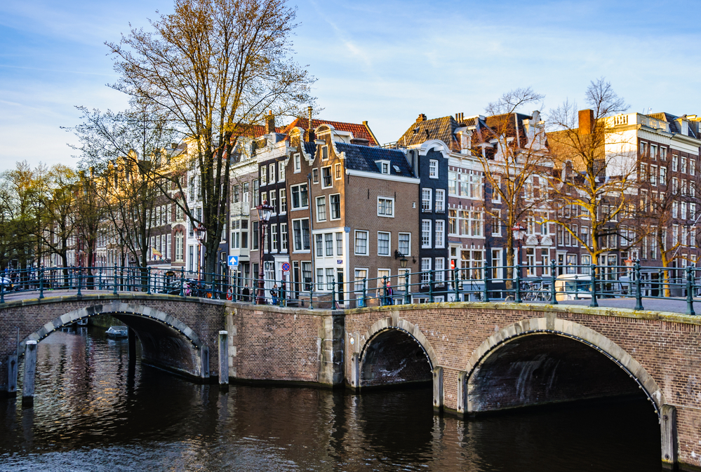 old-amsterdam-canal-houses-by-bridge-seen-from-waterside