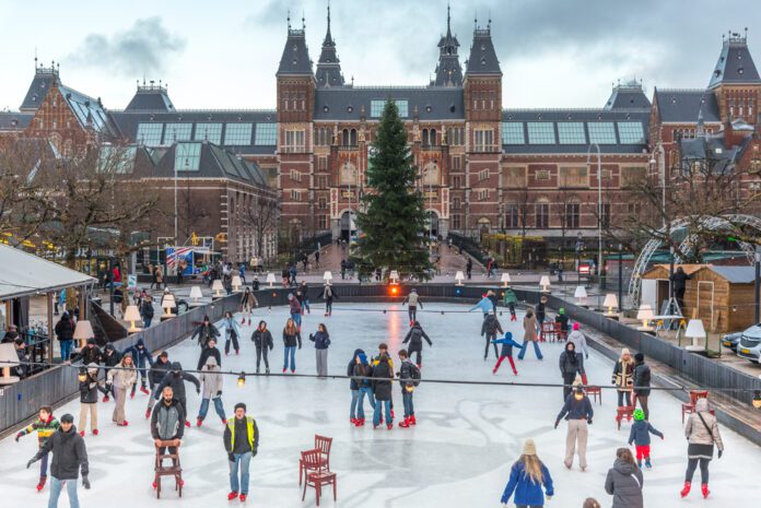 ice-skating-rink-in-amsterdam-in-the-museumplein-with-visitors-on-a-sunny-day-in-winter-with-the-rijskmuseum-in-the-background