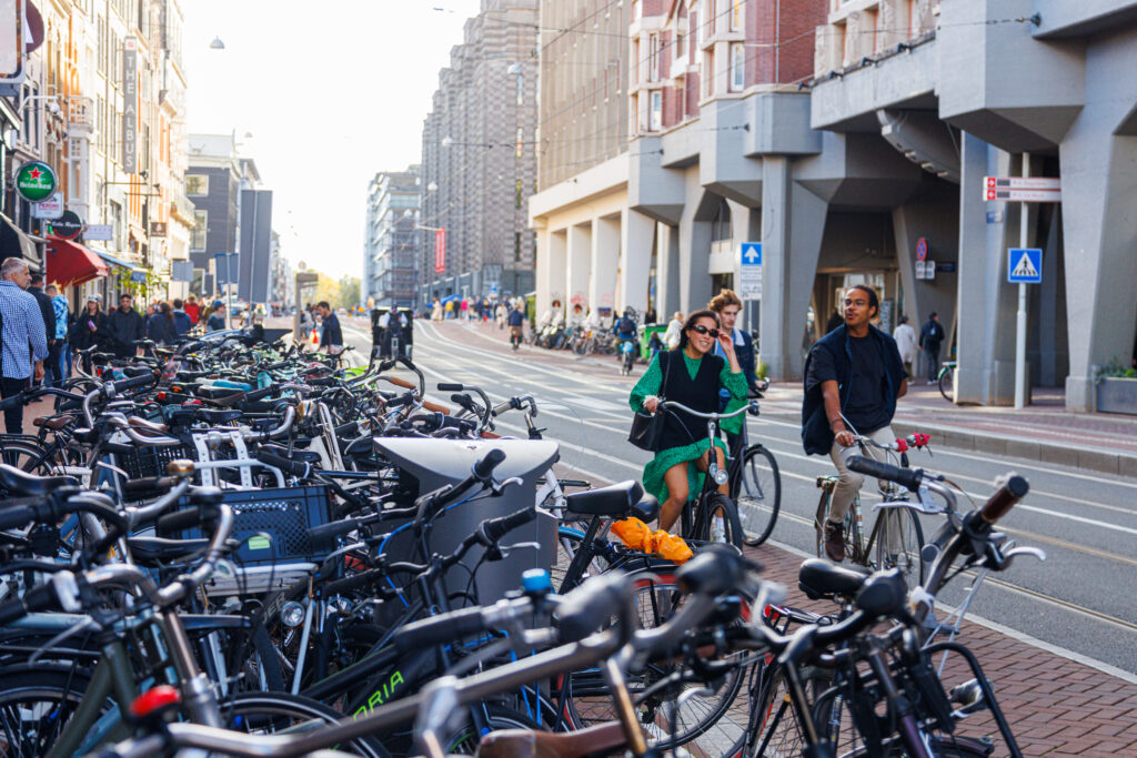 Three-people-biking-together-in-Amsterdam-with-other-bikes-next-to-them-making-Dutch-friends-through-biking