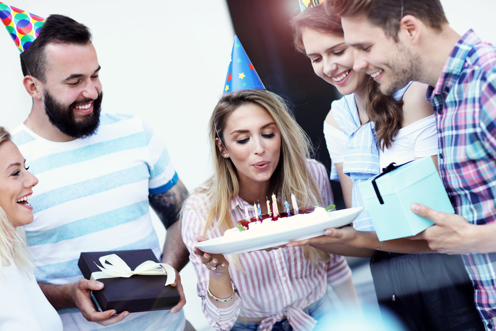 People-gathered-to-celebrate-a-womans-birthday-as-she-blows-out-the-candles