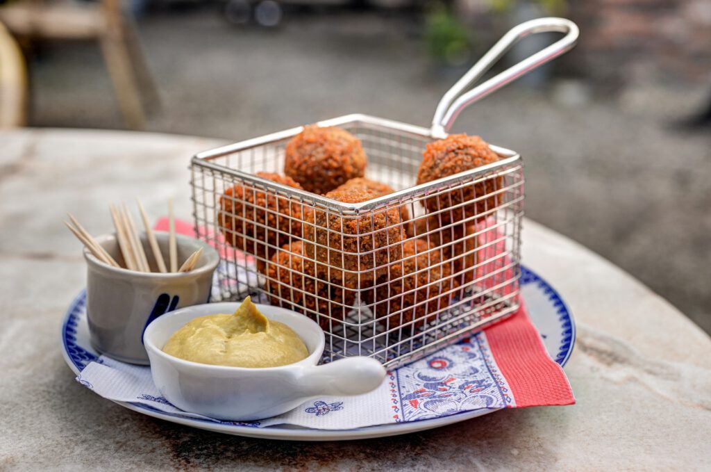 bitterballen-in-frying-pan-on-plate-next-to-sauce