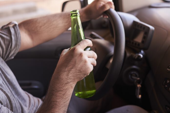 Free-photo-bottle-of-beer-in-a-man's-hands-driving-the-car-during-daytime
