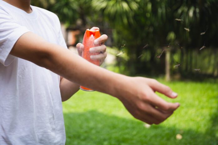 photo-of-boy-spraying-bug-repellent-on-his-arm-as-mosquitos-approach