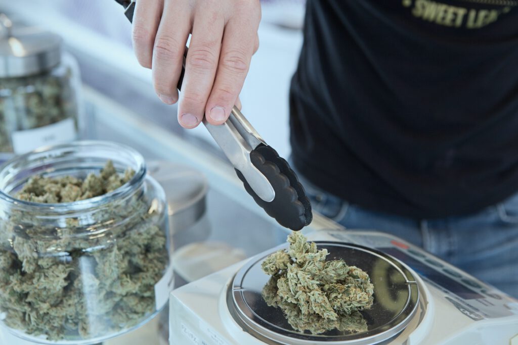 close-up-of-man-putting-weed-buds-on-scale-with-tongs