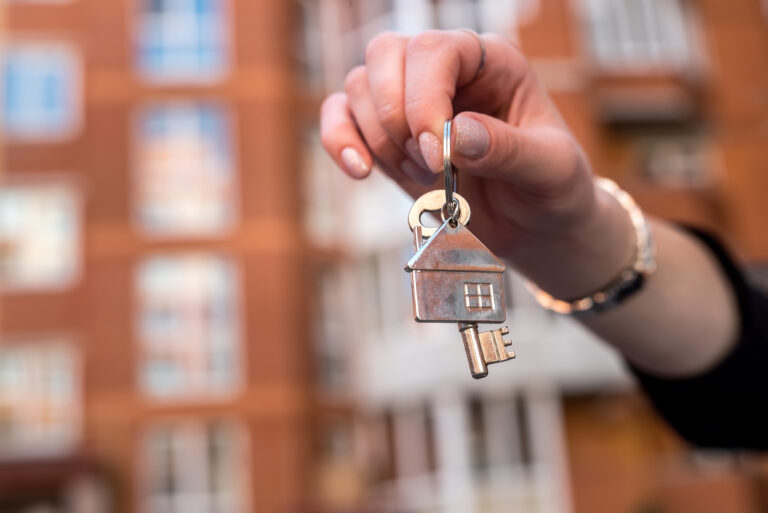 female-hand-holding-keys-in-front-of-a-new-built-home-in-the-netherlands