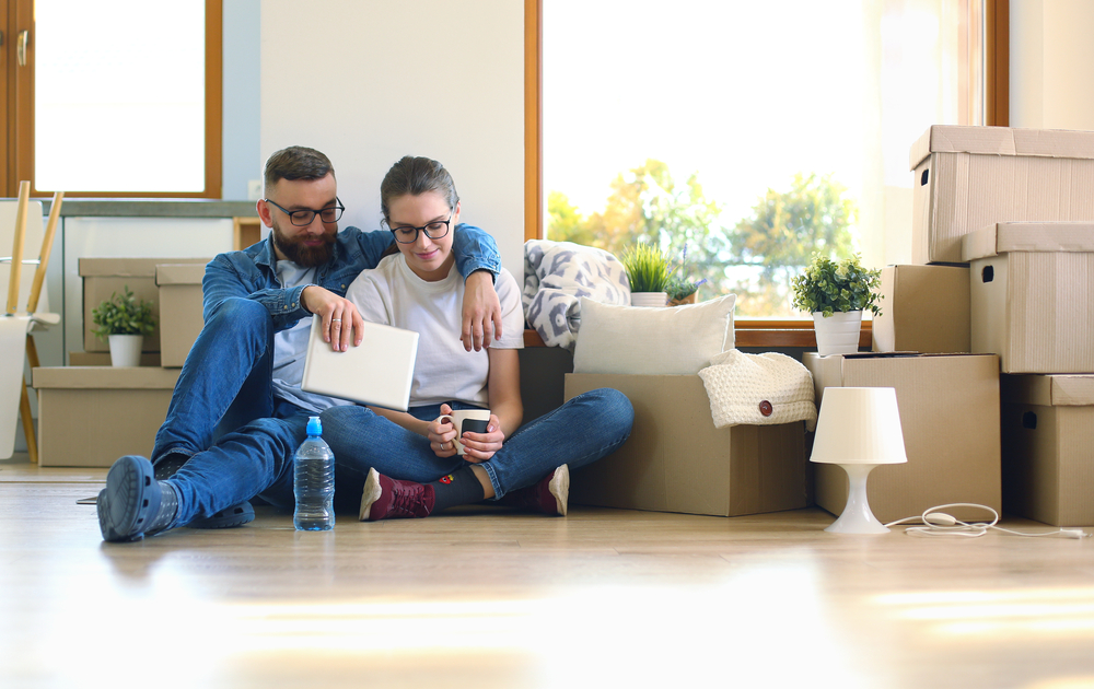 Photo-of-international-couple-sitting-on-floor-of-new-home-Netherlands-with-boxes