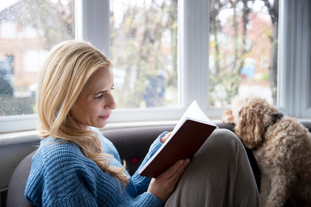 photo-of-woman-sitting-on-couch-near-window-in-the-netherlands-reading-book-to-learn-Dutch