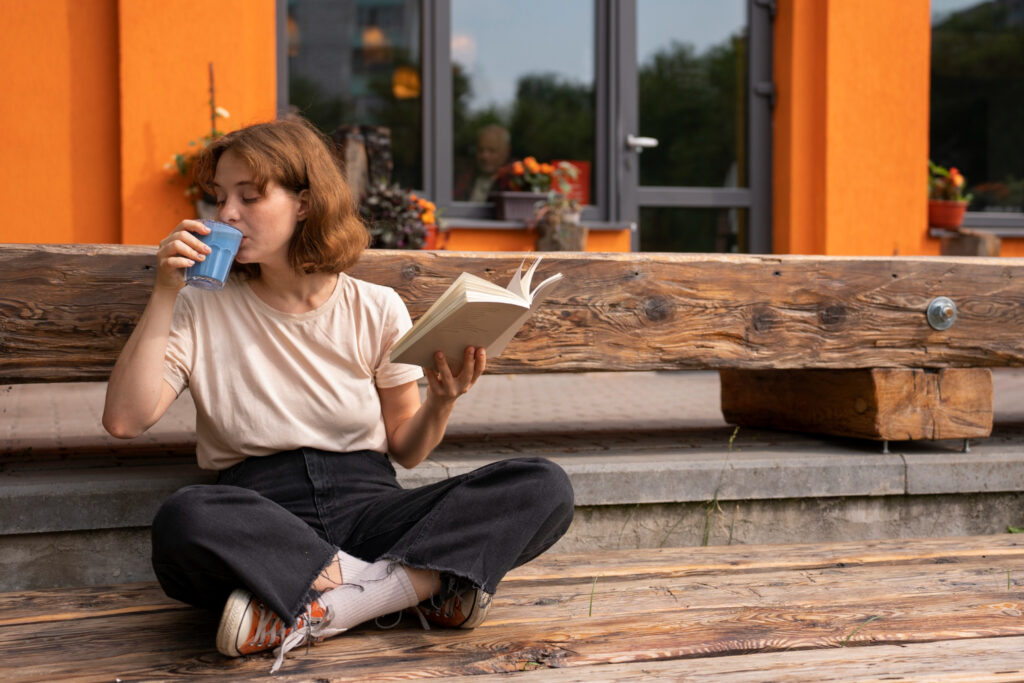 photo-of-woman-sitting-outside-cafe-drinking-coffee-learning-dutch-by-reading