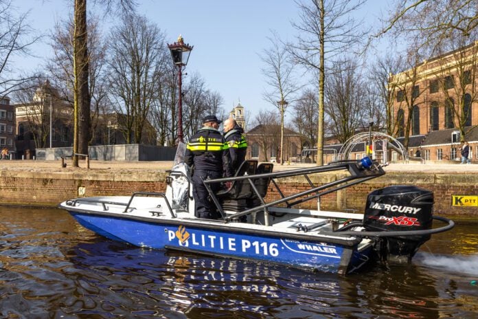 police-men-discussing-while-on-motoboat-on-dutch-canal-against-dutch-houses-and-city-view