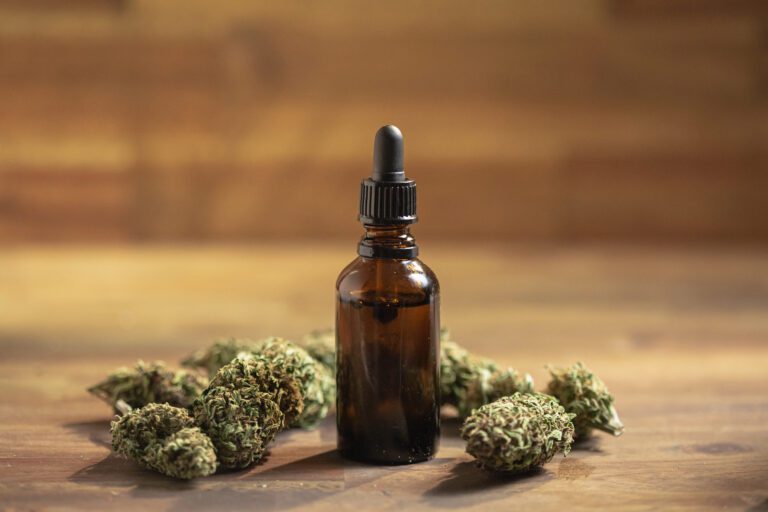 Dropper-with-medical-cannabis-CBD-oil-with-buds-on-table