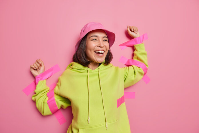 photo-of-laughing-asian-woman-stuck-to-pink-wall