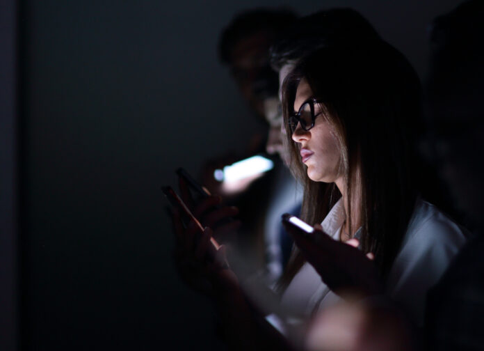 close-up-of-people-staring-at-their-phones-in-a-dark-train