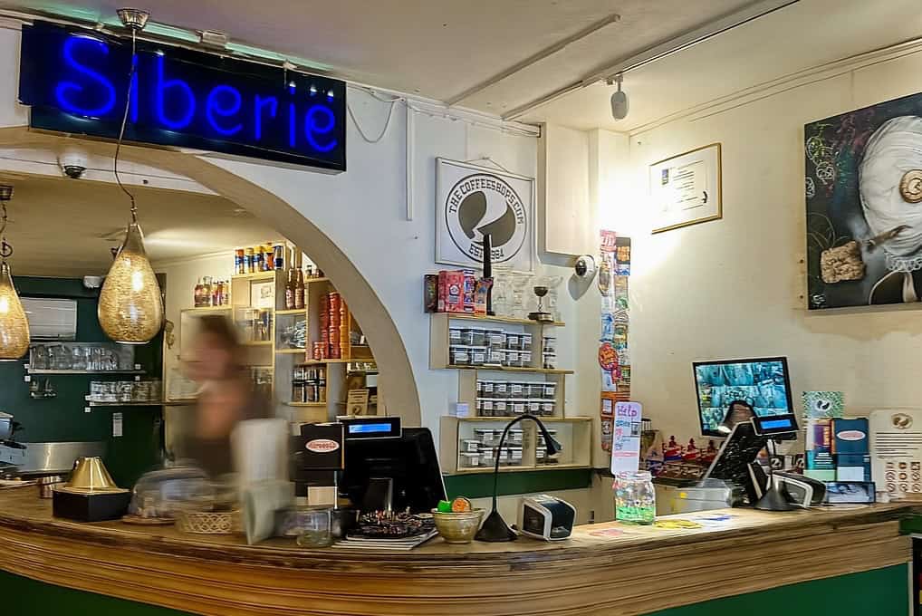photo-of-coffeeshop-siberie-interior-counter-with-eclectic-things-on-counter-art-and-blurred-person-moving
