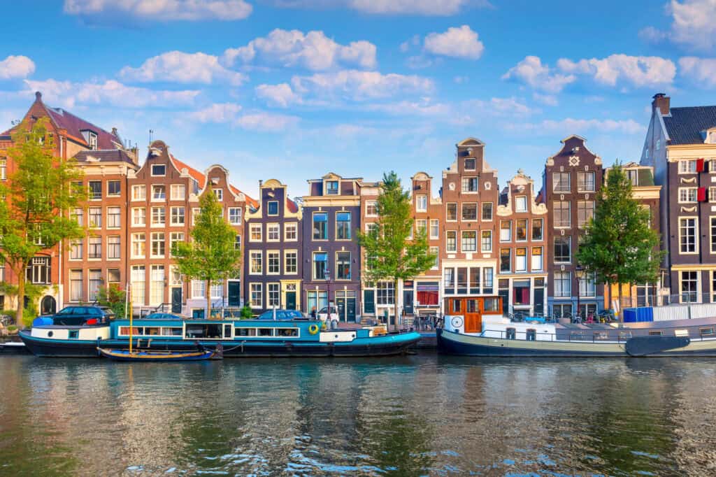 colourful-picture-of-boats-lining-amsterdam-canal-with-traditional-dutch-houses-in-the-background