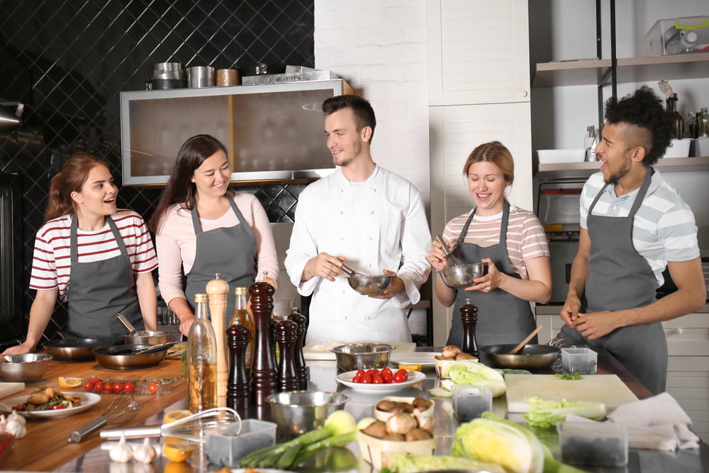 Group-of-young-people-in-a-kitchen-for-a-cooking-class-in-the-Netherlands-with-cooking-instructor-in-the-middle