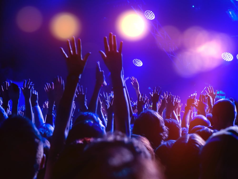 photo-of-people-on-dance-floor-in-purple-light-with-hands-in-air