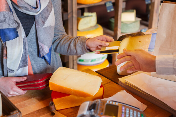 Customer paying for order of cheese in grocery shop, after taxes have increased.