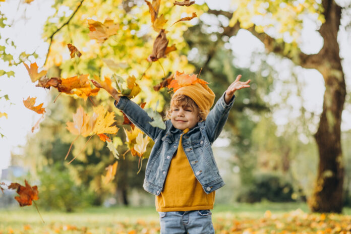 cute-boy-playing-with-leaves-autumn-park