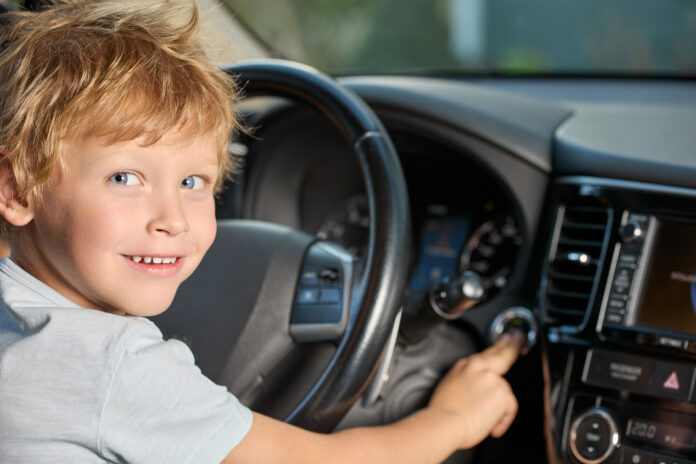 photo-of-child-driving-car-presses-engine-start-button-with-his-finger