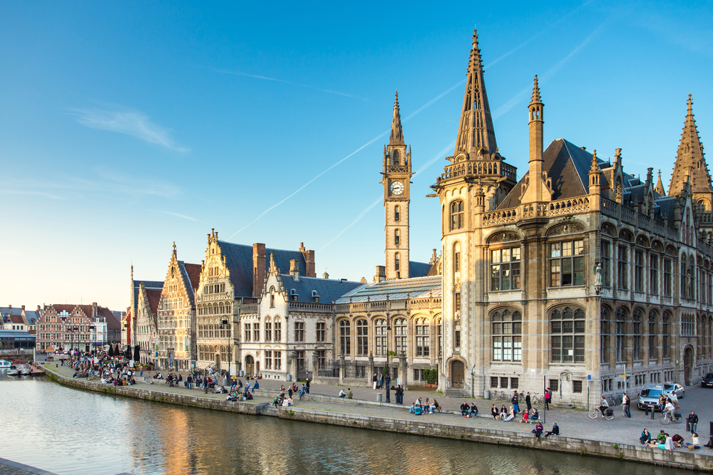 wide-angle-photo-of-historical-buildings-in-ghent-and-people-sitting-along-river-lys