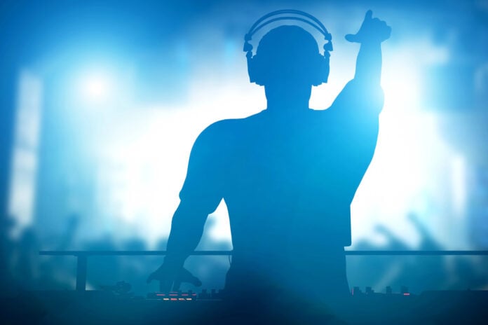 photo-of-dj-playing-set-in-front-of-crowd-with-arms-up