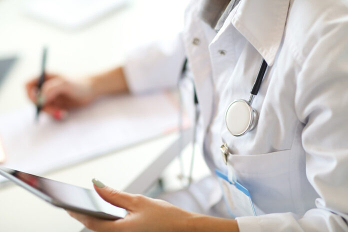 photo-of-doctor-in-uniform-making-notes-with-phone-in-hand