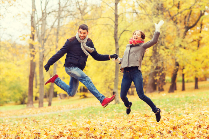 photo-of-couple-jumping-in-park-among-autumn-leaves