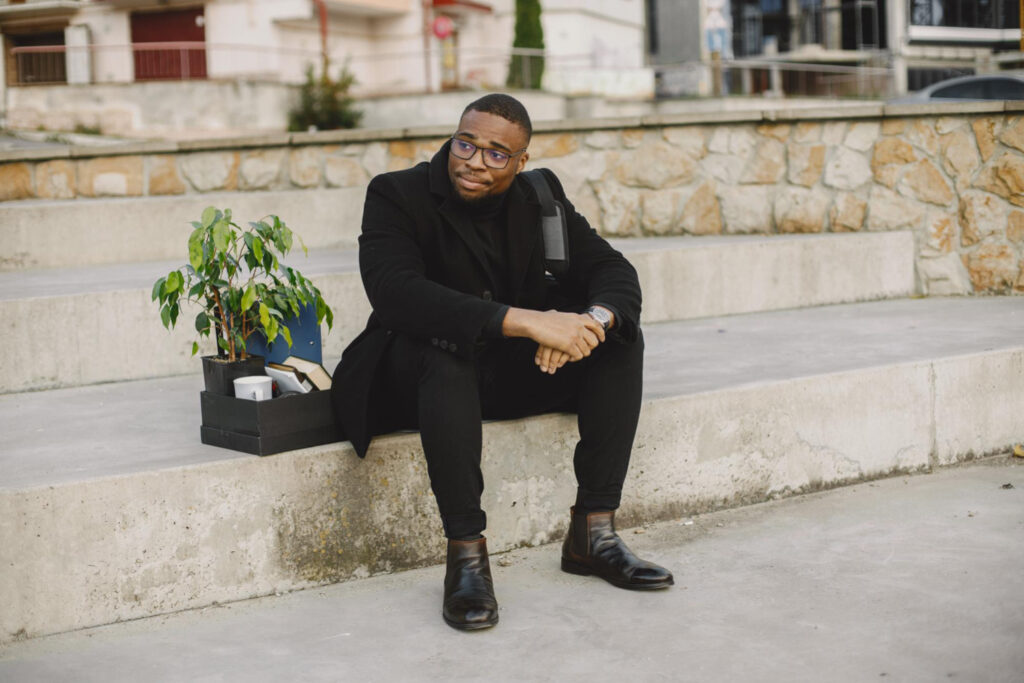 photo-of-fired-employee-sitting-on-wall-with-box-of-things-after-losing-job-in-netherlands