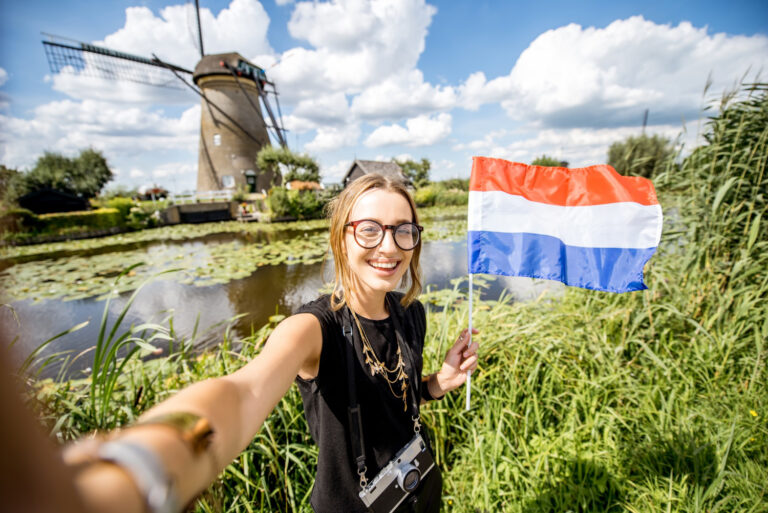 photo-of-woman-holding-dutch-flag-in-front-of-windmill-after-doing-Dutch-inburgering-exams-at-A2-level