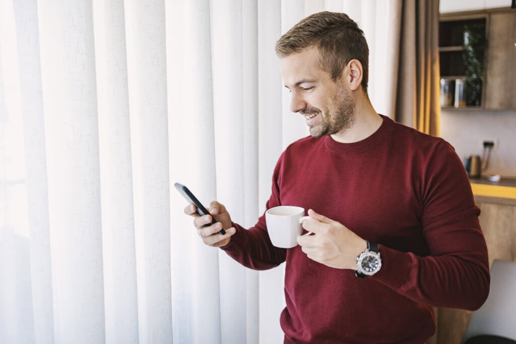 dutch-man-smiling-at-his-phone-while-he-grows-his-portfolio-with-crypto-investments