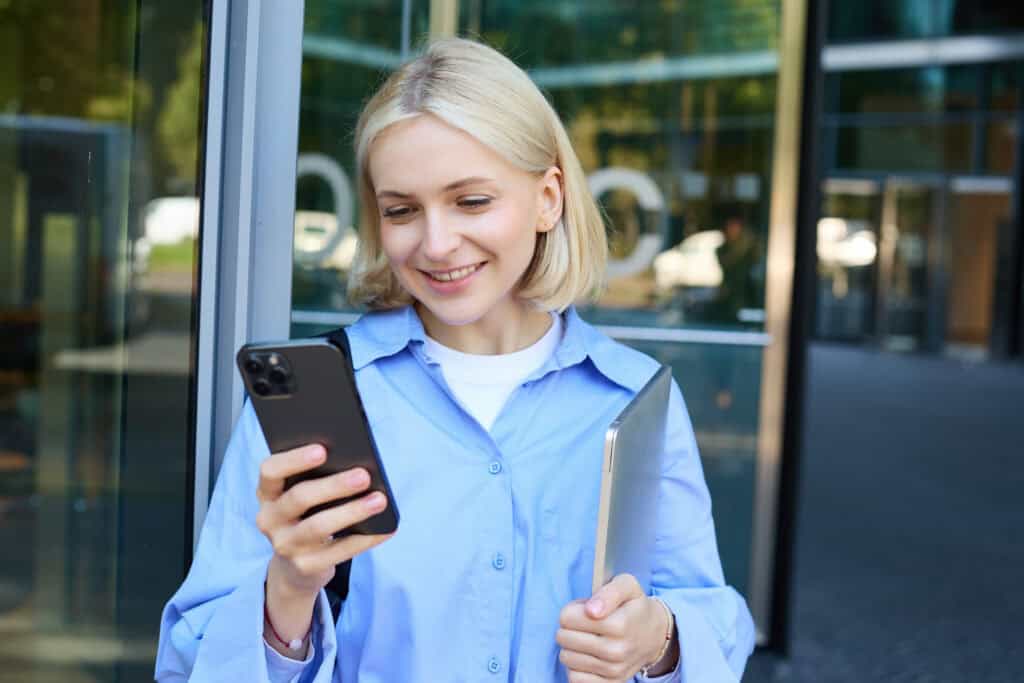 estudante universitário holandês saindo do prédio da faculdade segurando um telefone celular com cartão SIM grátis bsn