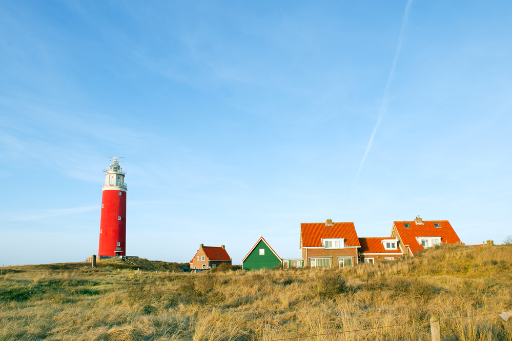 Red-lighthouse-with-village-in-the-dunes-from-Texel-islands-of-the-netherlands-dutch-islands-wadden-islands
