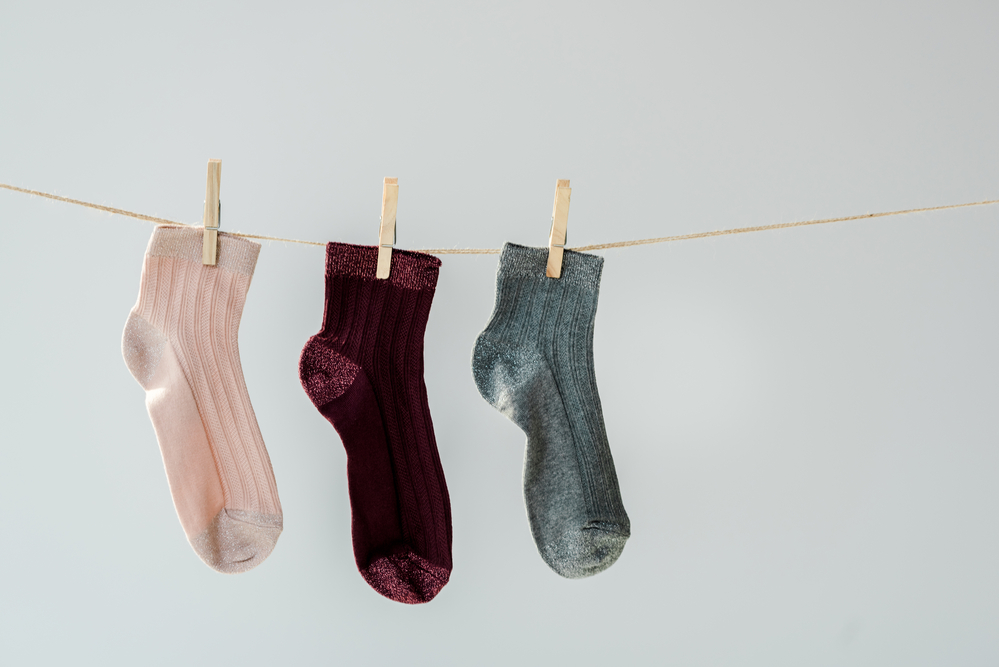 photo-of-three-socks-drying-on-a-drying-rack-with-a-grey-wall-in-the-background