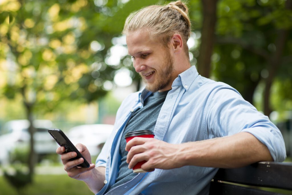 photo-of-dutchman-checking-his-mobile-banking-app-as-he-relaxes-on-a-park-bench-with-coffee