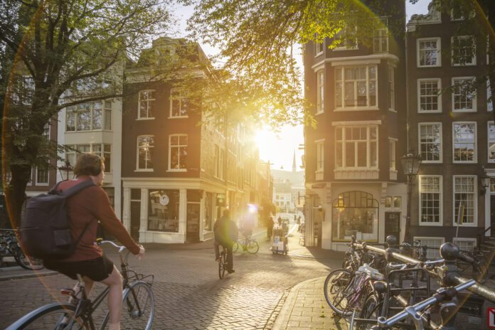 Artistic image of Amsterdam Early morning. People ride bicycles, the ancient European city of Amsterdam. Sunlight and silhouettes, beautiful downtown houses. Amsterdam, Holland, Netherlands, Europe