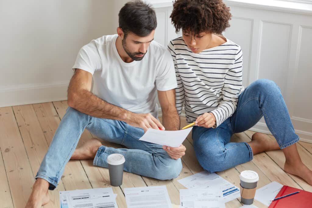 photo-of-man-and-woman-sitting-on-floor-looking-at-work-contracts-to-see-if-they-are-eligible-for-Dutch-mortgage-without-permanent-contract