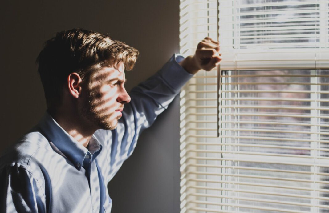 man-standing-in-front-of-window-blinds